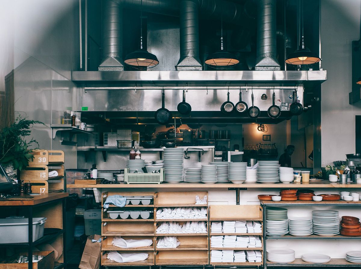 Une cuisine de restaurant ouverte avec casseroles, assiettes et étagères